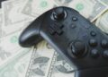 a video game controller sitting on top of a pile of money